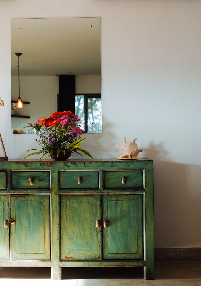 about-01 Stylish room with a vintage green cabinet, flower vase, and decorative shell.